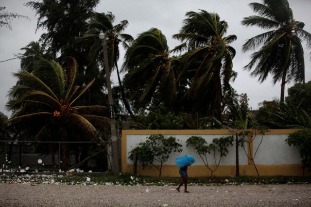 Una mujer se cubre de la lluvia provocada por la llegada del Huracán Matthew, en Les Cayes, Haití. 3 de octubre de 2016. Los haitianos que viven en chozas vulnerables frente al mar buscaban refugio en momentos en que el huracán Matthew, la tormenta caribeña más fuerte en nueve años, se acercaba al país y causaba mareas de tormenta, viento y lluvia en la costa. REUTERS/Andres Martinez Casares
