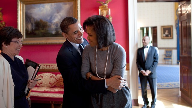 El presidente Obama abraza a la primera dama en el Salón Rojo mientras la consejera Valerie Jarrett sonríe antes de una recepción de la Asociación Nacional de Diarios y Editores en el año 2009 (Official White House Photo by Pete Souza)