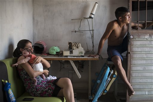 En esta imagen del 23 de diciembre de 2015, Angelica Pereira, a la izquierda, sostiene a su hija Luiza, nacida con microcefalia por el virus del zika, sentada cerca de su esposo Dejailson Arruda, en su casa de Santa Cruz do Capibaribe, en el estado de Pernambuco, Brasil. (AP Foto/Felipe Dana, Archivo)
