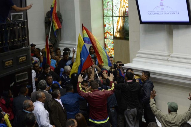 Supporters of Venezuelan President Nicolas Maduro force their way to the National Assembly during an extraoridinary session called by opposition leaders, in Caracas on October 23, 2016.  The opposition Democratic Unity Movement (MUD) called a Parliamentary session to debate putting President Nicolas Maduro on trial to "restore democracy" in an emergency session that descended into chaos as supporters of the leftist leader briefly seized the chamber. / AFP PHOTO / FEDERICO PARRA