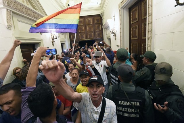Supporters of Venezuelan President Nicolas Maduro force their way to the National Assembly during an extraoridinary session called by opposition leaders, in Caracas on October 23, 2016. The opposition Democratic Unity Movement (MUD) called a Parliamentary session to debate putting President Nicolas Maduro on trial to "restore democracy" in an emergency session that descended into chaos as supporters of the leftist leader briefly seized the chamber. / AFP PHOTO / JUAN BARRETO