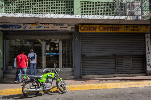 CAR01. CARACAS (VENEZUELA), 28/10/2016.- Un local comercial abierto y otro cerrado hoy, viernes 28 de octubre de 2016, en Caracas (Venezuela). El paro general de 12 horas convocado por la oposición venezolana se cumple a medias en el país pues tanto las entidades bancarias como algunos comercios y oficinas abrieron sus puertas, sin embargo, las principales vías se mostraron con mucho menos tráfico que el que se observa en un día laboral normal. EFE/MIGUEL GUTIÈRREZ