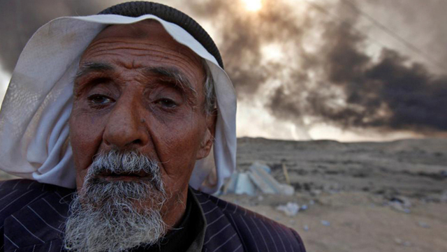 Un hombre regresa a su pueblo después de haber sido liberado del EI en el pueblo de Qayyara, al sur de Mosul. Al fondo, pozos de petróleo estatales incendiados por el grupo terrorista.