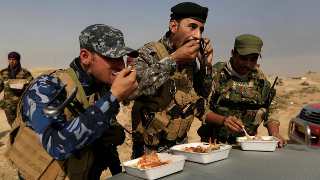Miembros de las fuerzas iraquíes almuerzan ante las posiciones del EI en la ciudad de Safayah, cerca de Mosul.