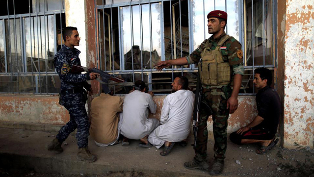 Soldados del Ejército iraquí hacen guardia sobre presuntos militantes del EI en Qayyara.