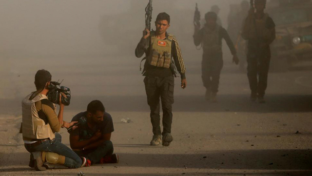 Un periodista iraquí junto a una de las víctimas de un ataque suicida del EI con un coche bomba durante enfrentamientos en Bartella.