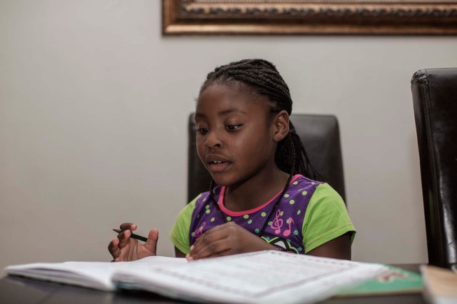 Seven-year-old author Michelle Nkamankeng looks at her homework at her house on October 26, 2016 in Johannesburg, South Africa.  Michelle Nkamankeng has made history by being the youngest author from the African continent to make it in the top 10 youngest writers in the world.  / AFP PHOTO / GIANLUIGI GUERCIA