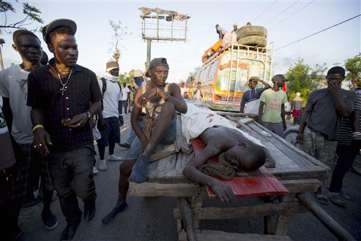 En esta imagen del 1 de noviembre de 2016, manifestantes cargan el cuerpo de un adolescente en un carro después de que fuera baleado en las protestas por los retrasos en el reparto de ayuda tras un huracán de categoría 4 en Haití el mes pasado, en Les Cayes, Haití. ( AP Foto/Dieu Nalio Chery)
