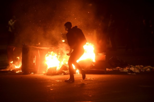 Una mujer pasa frente a un auto incendiado durante una manifestación en Oakland, California, luego de la elección de Donald Trump como presidente de Estados Unidos. REUTERS/Noah Berger