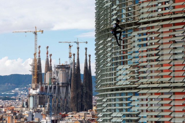 French climber Alain Robert, also known as "The French Spiderman", scales the 38-story skyscraper Torre Agbar with the Sagrada Familia cathedral in the background in Barcelona, Spain, November 25, 2016. REUTERS/Albert Gea TPX IMAGES OF THE DAY