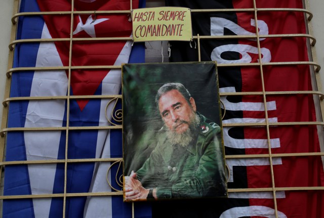 A picture of Cuba's former president Fidel Castro hangs on a window between a Cuban flag (L) and a Fidel Castro's 26th of July guerrilla movement flag in Artemisa province, Cuba November 27, 2016. The words over the picture read, " Eternally commander." REUTERS/Enrique de la Osa