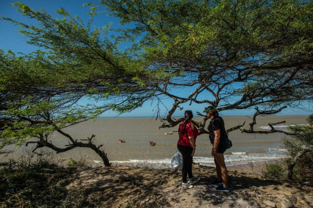 Dos inmigrantes esperan el bote que los sacará de Venezuela. Credit Meridith Kohut para The New York Times