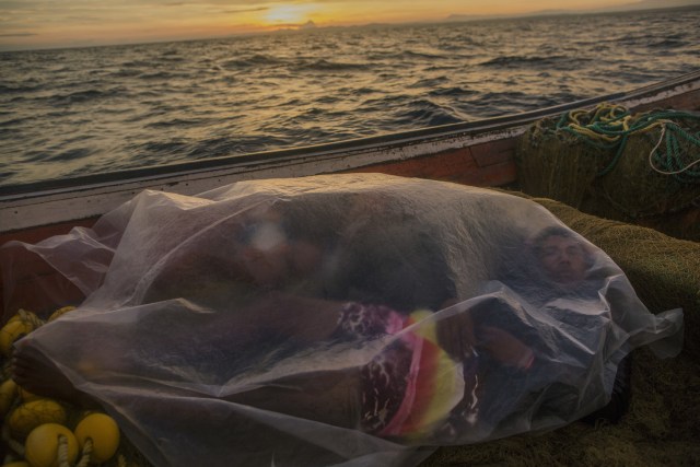 En esta imagen, tomada el 8 de noviembre de 2016, Jorge Marval duerme una siesta en su barco, bajo un plástico, tras pescar durante toda la noche, al amanecer en Punta de Araya, en el estado de Sucre, Venezuela. El negocio de la pesca se vino abajo en Venezuela, como casi todas las industrias del país. (AP Foto/Rodrigo Abd)