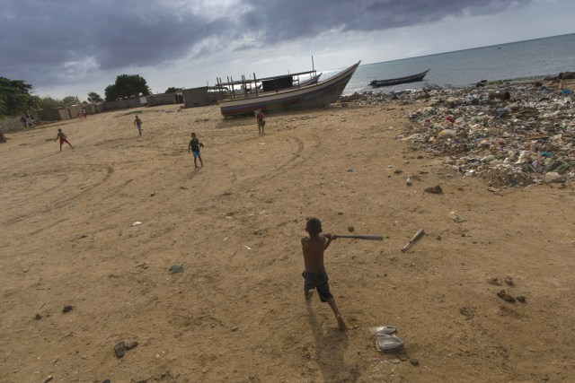 En esta imagen, tomada el 8 de noviembre de 2016, niños juegan al béisbol en la playa, en Punta de Araya, en el estado de Sucre, Venezuela. Algunas empresas privadas emigraron a otros países porque el gobierno les exige que vendan la mitad de lo que capturan en bolívares que no valen casi nada. (AP Foto/Rodrigo Abd)
