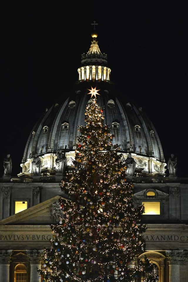 The Christmas tree is pictured in front of the Saint Peter dome at the Saint Peter's square following its illumination on December 9, 2016 in Vatican. This year, the Christmas ornaments were made by children of the paediatric oncology departments of Italian hospitals. / AFP PHOTO / VINCENZO PINTO