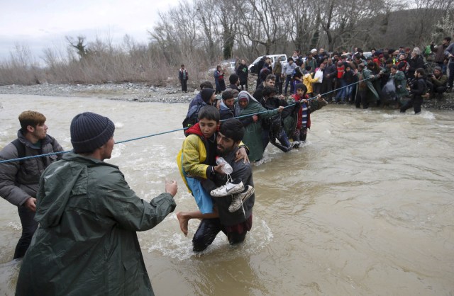 FILE PHOTO - Refugees and migrants wade across a river near the Greek-Macedonian border, west of the the village of Idomeni, Greece, March 14, 2016. REUTERS/Stoyan Nenov/File Photo REUTERS PICTURES OF THE YEAR 2016 - SEARCH 'POY 2016' TO FIND ALL IMAGES
