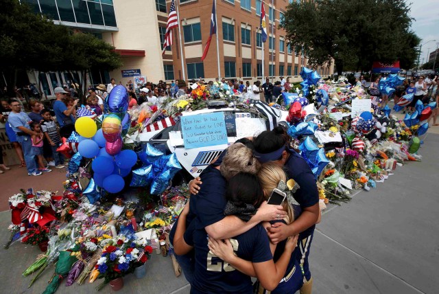 FILE PHOTO - A softball team hugs after paying their respects at a makeshift memorial at Dallas Police Headquarters following the multiple police shootings in Dallas, Texas, U.S., July 9, 2016. REUTERS/Carlo Allegri/File Photo REUTERS PICTURES OF THE YEAR 2016 - SEARCH 'POY 2016' TO FIND ALL IMAGES