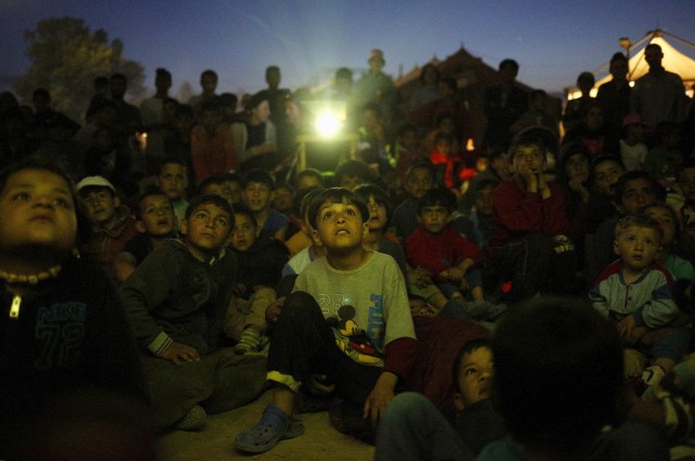 FILE PHOTO - Children watch a cartoon movie, screened at a makeshift camp for migrants and refugees at the Greek-Macedonian border near the village of Idomeni, Greece, April 17, 2016. REUTERS/Stoyan Nenov/File Photo REUTERS PICTURES OF THE YEAR 2016 - SEARCH 'POY 2016' TO FIND ALL IMAGES