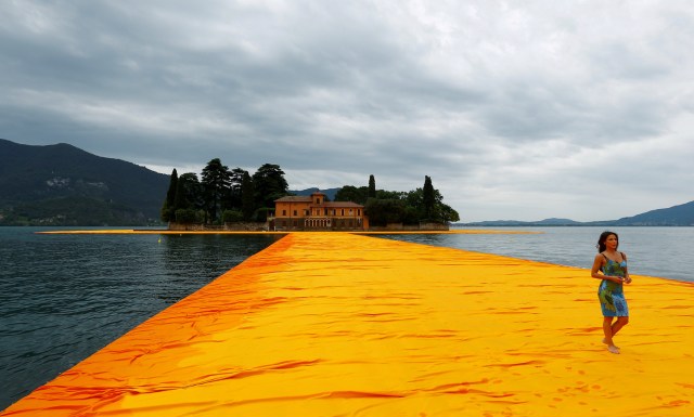 FILE PHOTO - A woman walks on the installation 'The Floating Piers' by Bulgarian-born artist Christo Vladimirov Yavachev known as Christo, on the Lake Iseo, northern Italy, June 16, 2016. REUTERS/Stefano Rellandini/File Photo REUTERS PICTURES OF THE YEAR 2016 - SEARCH 'POY 2016' TO FIND ALL IMAGES