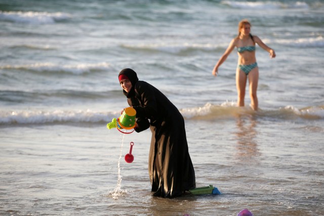 FILE PHOTO - A Muslim woman wearing a Hijab stands in the waters in the Mediterranean Sea as an Israeli stands nearby on the beach in Tel Aviv, Israel August 21, 2016. REUTERS/Baz Ratner/File Photo REUTERS PICTURES OF THE YEAR 2016 - SEARCH 'POY 2016' TO FIND ALL IMAGES