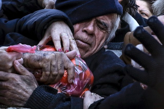 FILE PHOTO - A man grasps a bag of tangerines as people receive free produce, handed out by farmers, during a protest over the government's proposal to overhaul the country's ailing pension system in Athens, Greece, January 27, 2016. REUTERS/Alkis Konstantinidis/File Photo REUTERS PICTURES OF THE YEAR 2016 - SEARCH 'POY 2016' TO FIND ALL IMAGES