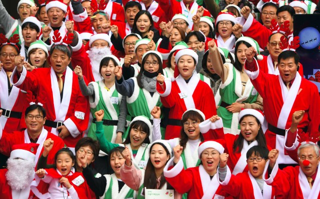 South Korean volunteers in Santa Claus outfits cheer before heading out to distribute Christmas gifts at homes for prematurely born babies in Seoul on December 8, 2016. The volunteers will visit some 40 homes raising prematurely born babies in Seoul and the surrounding Gyeonggi Province. / AFP PHOTO / JUNG Yeon-Je