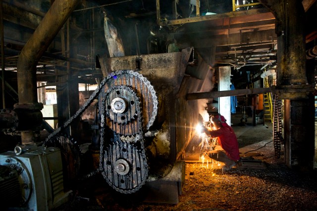 En esta foto del 3 de noviembre de 2016, un trabajador repara una máquina para la próxima zafra en el ingenio azucarero de Cumanacoa, estado de Sucre, Venezuela. (AP Foto/Rodrigo Abd)