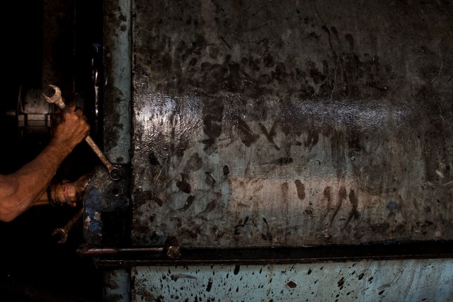 En esta foto del 3 de noviembre de 2016, un trabajador repara una máquina de cara a la próxima zafra en el ingenio azucarero en Cumanacoa, estado de Sucre, Venezuela. Los ingenios y las plantas de procesamiento de pescado trabajan ahora a la mitad de su capacidad. (AP Foto/Rodrigo Abd)