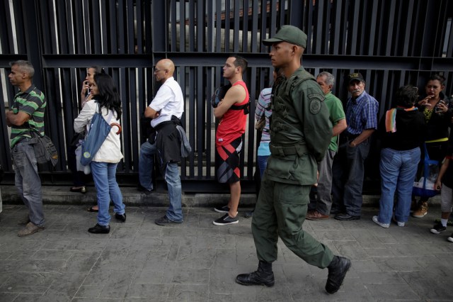 A Venezuelan soldier controls the crowd as people line up to get into a Banco Mercantil branch in Caracas, Venezuela December 13, 2016. REUTERS/Marco Bello