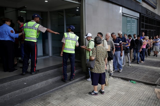Police officers control the crowd as people line up to get into a Banesco bank branch in Caracas, Venezuela December 13, 2016. REUTERS/Marco Bello