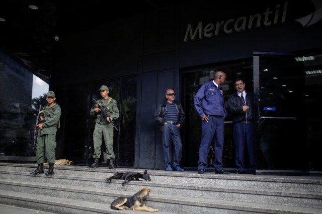 Venezuelan soldiers stand guard at the entrance of a Banco Mercantil branch in Caracas, Venezuela December 13, 2016. REUTERS/Marco Bello