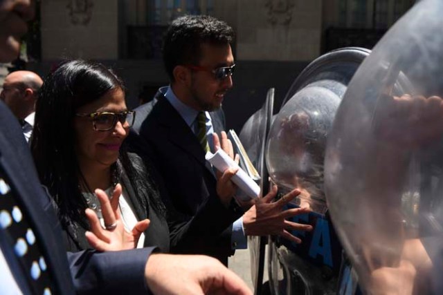 Venezuela's Foreign Minister Delcy Rodriguez, is blocked by riot police officers before entering the Argentine Foreign Ministry in Buenos Aires during a meeting among Mercosur's ministers where Venezuela was not invited, on December 14, 2016. Mercosur's foreign ministers debate on Venezuela's suspension from the group after accusations that the leftist government in Caracas failed to meet democratic and trade standards. / AFP PHOTO / EITAN ABRAMOVICH