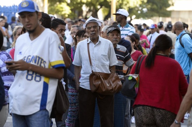 People queue outside Venezuela's Central Bank (BCV) in Caracas in an attempt to change 100 Bolivar notes, on December 16, 2016. Venezuelans lined up to deposit 100-unit banknotes before they turned worthless, but replacement bills had yet to arrive, increasing the cash chaos in the country with the world's highest inflation. Venezuelans are stuck in currency limbo after President Nicolas Maduro ordered the 100-bolivar note -- the largest denomination, currently worth about three US cents -- removed from circulation in 72 hours. / AFP PHOTO / FEDERICO PARRA