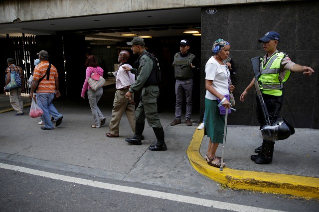 Venezuelan National Guard members and a police officer control the crowd as people queue to deposit their 100 bolivar notes, outside Venezuela's Central Bank in Caracas, Venezuela December 16, 2016. REUTERS/Marco Bello