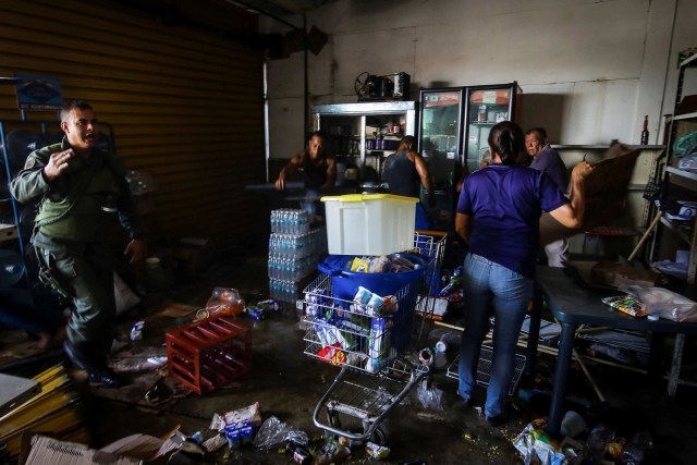 A Venezuelan National Guard talks to employees and neighbors as they recover the valuables after a supermarket was looted in Ciudad Bolivar, Venezuela December 19, 2016. REUTERS/William Urdaneta EDITORIAL USE ONLY. NO RESALES. NO ARCHIVE.
