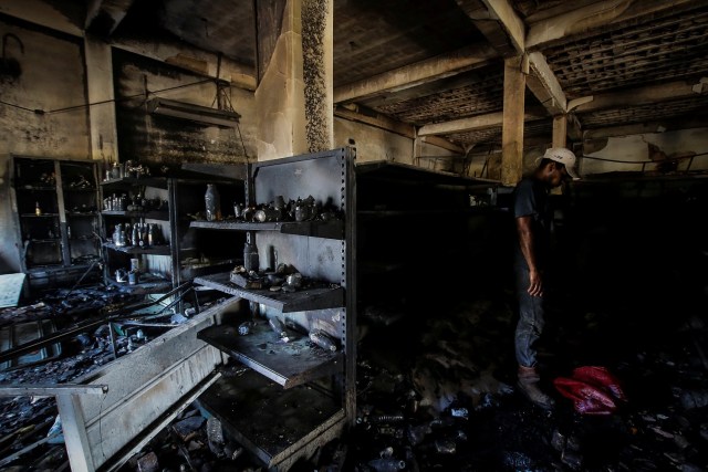 An employee stands next to damaged shelves in a store after it was looted in Ciudad Bolivar, Venezuela December 19, 2016. REUTERS/William Urdaneta EDITORIAL USE ONLY. NO RESALES. NO ARCHIVE.