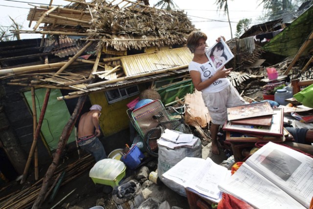 FRM203 POLANGUI (FILIPINAS) 26/12/2016.- Una residente recupera objetos personales después de que su casa resultara dañada por el paso del tifón Nock-Ten por la localidad de Polangui, provincia de Albay (Filipinas) hoy, 26 de diciembre de 2016. Al menos tres personas han muerto en Filipinas durante el paso del tifón Nock-Ten que continúa hoy su avance por el archipiélago con fuertes vientos y copiosas lluvias, informan las autoridades locales. EFE/Zalrian Sayat