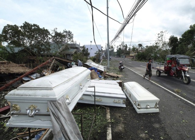 FRM212 POLANGUI (FILIPINAS) 26/12/2016.- Un residente pasa junto a varios ataúdes esparcidos por el suelo tras el paso del tifón Nock-Ten por la localidad de Polangui, provincia de Albay (Filipinas) hoy, 26 de diciembre de 2016. Al menos tres personas han muerto en Filipinas durante el paso del tifón Nock-Ten que continúa hoy su avance por el archipiélago con fuertes vientos y copiosas lluvias, informan las autoridades locales. EFE/Zalrian Sayat