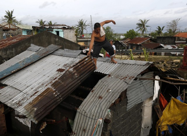 FRM223 PAMPLONA (FILIPINAS) 26/12/2016.- Un lugareño trabaja en la reparación del tejado de su casa tras el paso del tifón Nock-Ten por la localidad de Pamplona, Camarines Sur (Filipinas), hoy, 26 de diciembre de 2016. Al menos tres personas han muerto en Filipinas durante el paso del tifón Nock-Ten que continúa hoy su avance por el archipiélago con fuertes vientos y copiosas lluvias, informan las autoridades locales. EFE/Francis R. Malasig