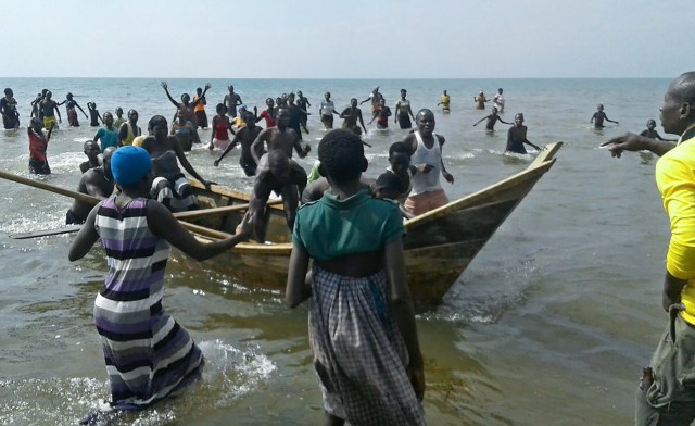 Survivors of a boat accident come back ashore on Lake Albert, on December 26, 2016 in Buliisa, after at least 30 Ugandan members of a village football team and their fans drowned when their boat capsized on Lake Albert during a party. Police officers working with local fishermen managed to rescue 15 of the revellers, who were heading from the village of Kaweibanda in the western Buliisa District to watch a friendly Christmas Day match in Hoima District, Rutagira said. / AFP PHOTO / -