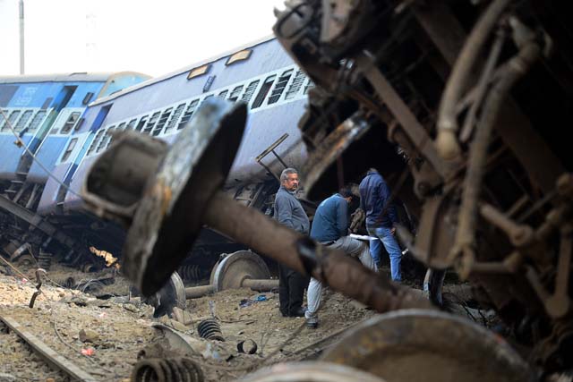 Indian officials gather at the wreckage of train carriages at Rura, some 30 kms west of Kanpur on December 28, 2016, following a train crash in the northern Indian state of Uttar Pradesh. At least two people died and 28 were injured after a train derailed in north India, close to the site of a previous rail accident that killed 146. / AFP PHOTO / Sanjay KANOJIA