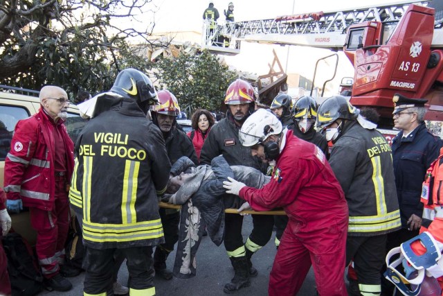 ITA01 ROMA (ITALIA), 28/12/2016.- Varios bomberos portan una camilla con el cuerpo de una mujer encontrada entre los escombros de un edificio colapsado en Acilia, Italia, hoy 28 de diciembre de 2016. Al menos dos personas fueron rescatadas de un edificio hundido tras una fuga de gas. EFE/Massimo Percossi