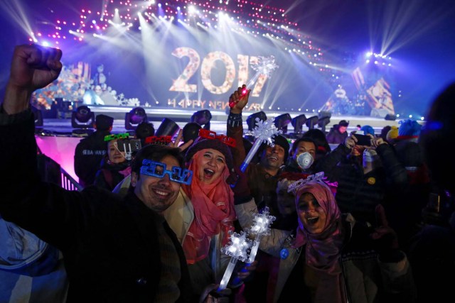 People pose for pictures as they attend a New Year's Eve countdown event in Beijing, China, December 31, 2016. REUTERS/Thomas Peter