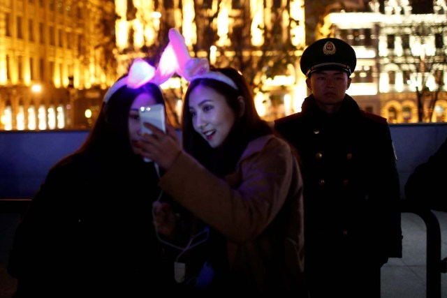 REFILE - CORRECTING TYPO Women take a selfie next to a police officer as they take part in New Year's Eve celebrations on the Bund, in Shanghai, China December 31, 2016. REUTERS/Aly Song