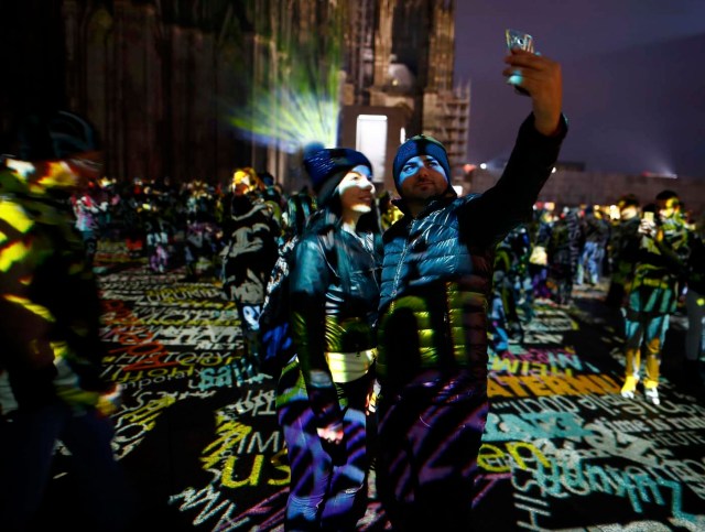 People take a selfie during the laser installation "Time Drifts Cologne" before New Year celebrations for 2017 in Cologne, Germany, December 31, 2016. REUTERS/Wolfgang Rattay