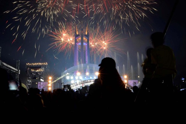 Revellers watch as fireworks explode over the Quezon Memorial Circle during New Year's celebrations in Quezon City, Metro Manila, Philippines January 1, 2017. REUTERS/Ezra Acayan