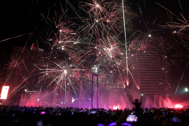 People watch fireworks explode around the Selamat Datang Monument during New Year's Eve celebrations in Jakarta, Indonesia December 31, 2016. REUTERS/Beawiharta