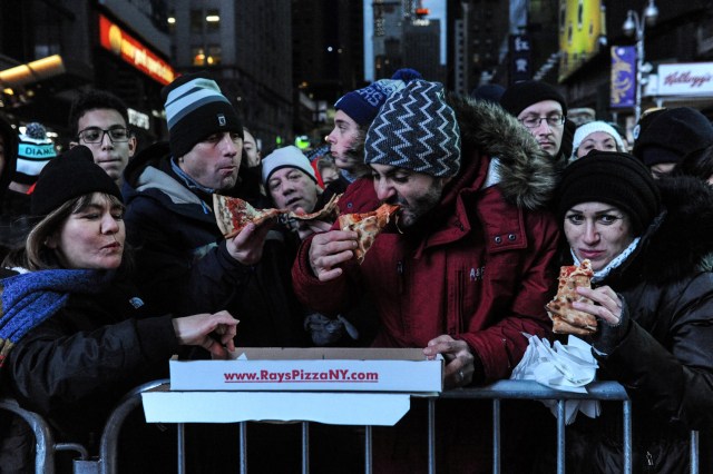 People have a pizza delivered while waiting for the events to begin in Times Square on New Year's Eve in New York, U.S. December 31, 2016.  REUTERS/Stephanie Keith