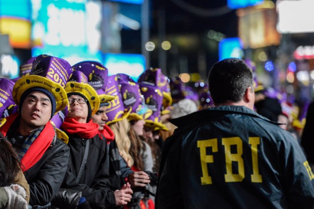 An FBI agent walks past revelers gathered in Times Square on New Year's Eve in New York, U.S. December 31, 2016. REUTERS/Stephanie Keith