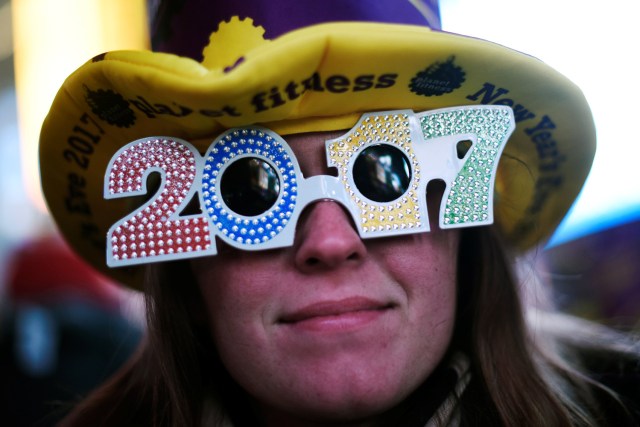 A reveler poses for a photo as she wears glasses that read "2017" in during New Year's Eve festivities in the Times Square area of New York, December 31, 2016. REUTERS/Mark Kauzlarich